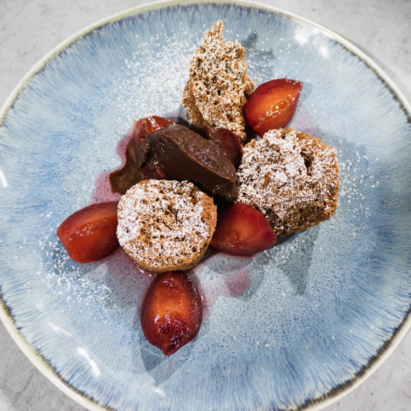 Schokoladenmousse mit Früchten und Kuchen auf blauem Teller