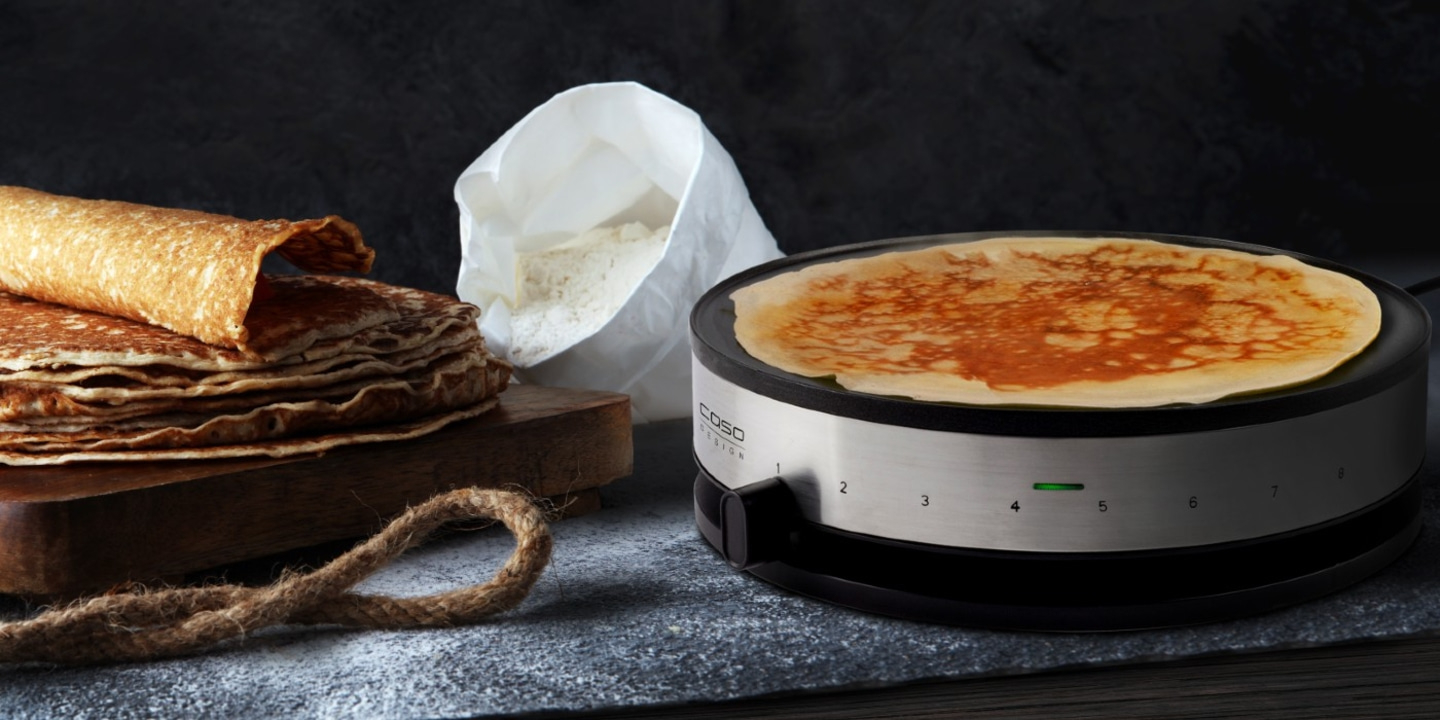 Crêpes auf einem Crêpes-Maker mit Zutaten und Dekoration.
