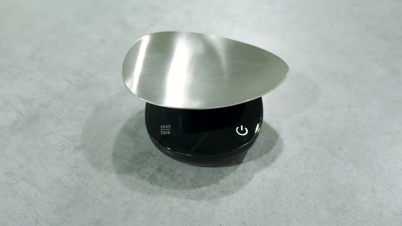 A digital kitchen scale with a stainless steel bowl on a gray surface.