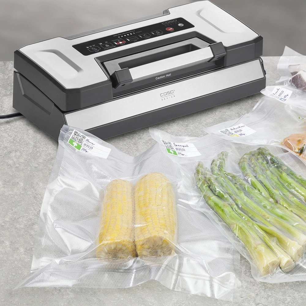 Vakuumiergerät mit Mais, Spargel und Fleisch in Beuteln.