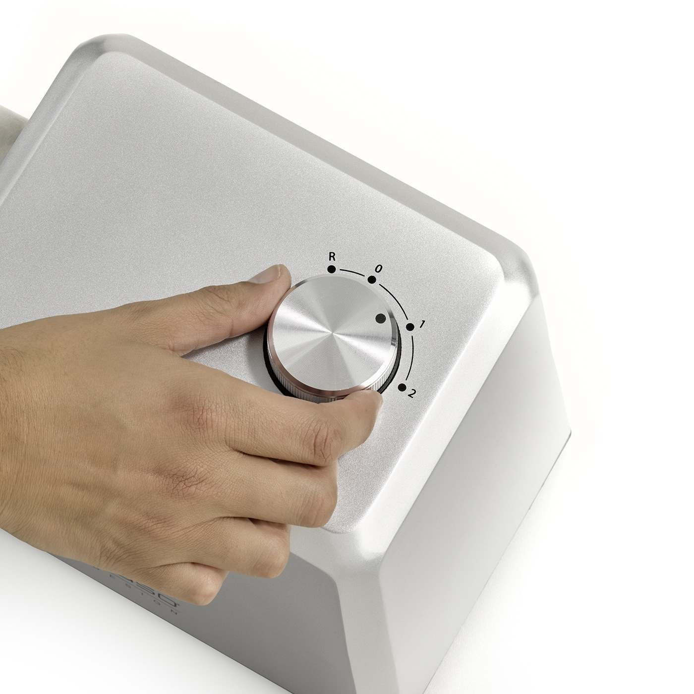Hand turning silver knob with R, 0, 1, 2 markings on white background