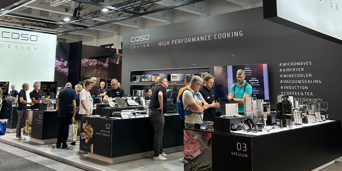 Ausstellung von Küchengeräten mit vielen Besuchern und dem Logo 'COSO DESIGN'.