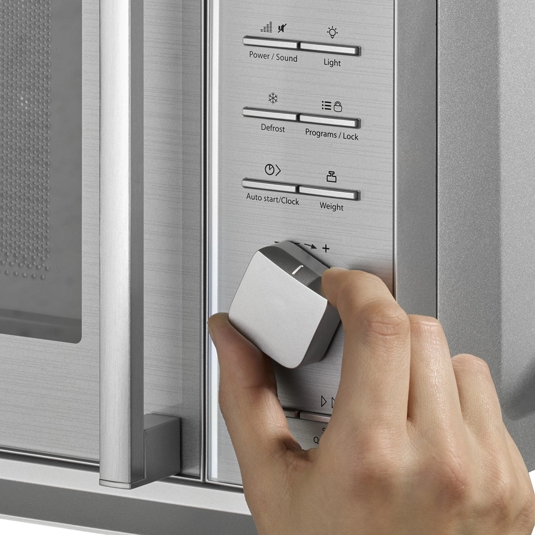 Microwave with controls and hand turning a knob to adjust settings, close-up shot.