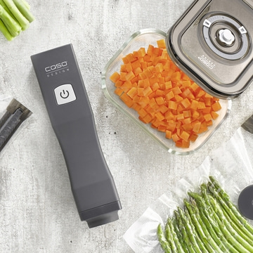 Vacuum sealer with vegetables and asparagus on a gray background.