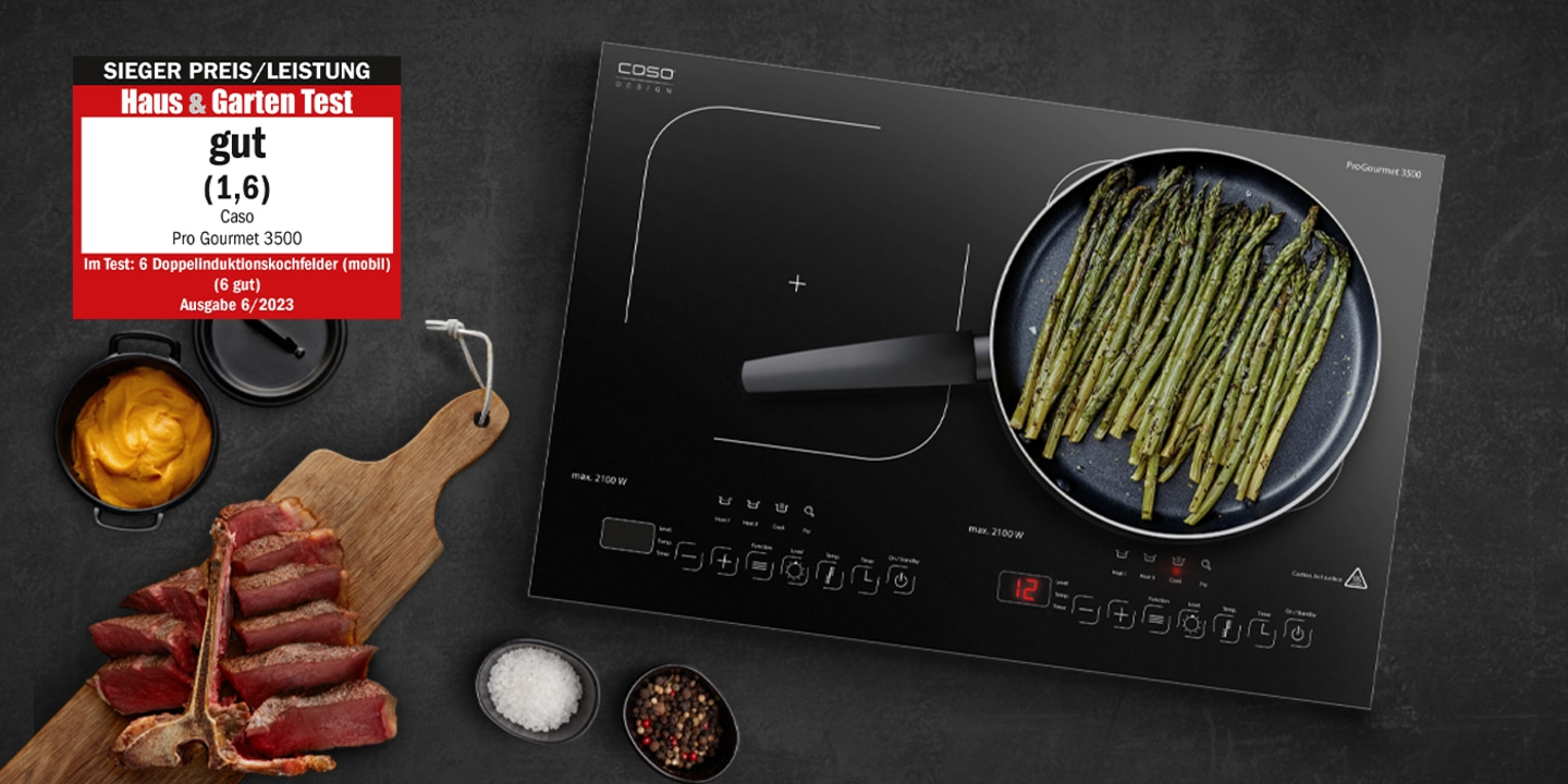 Induction cooktop with asparagus and meat, 'good' rating from Haus & Garten Test.