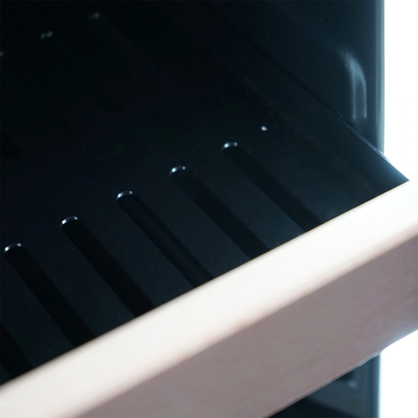 Close-up of black shelf with light brown frame and slots