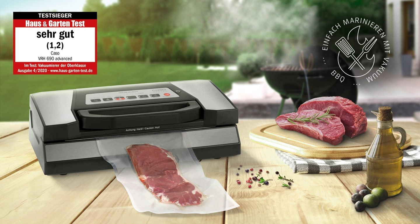 Vacuum sealer with meat, BBQ and test award on wooden table outdoors