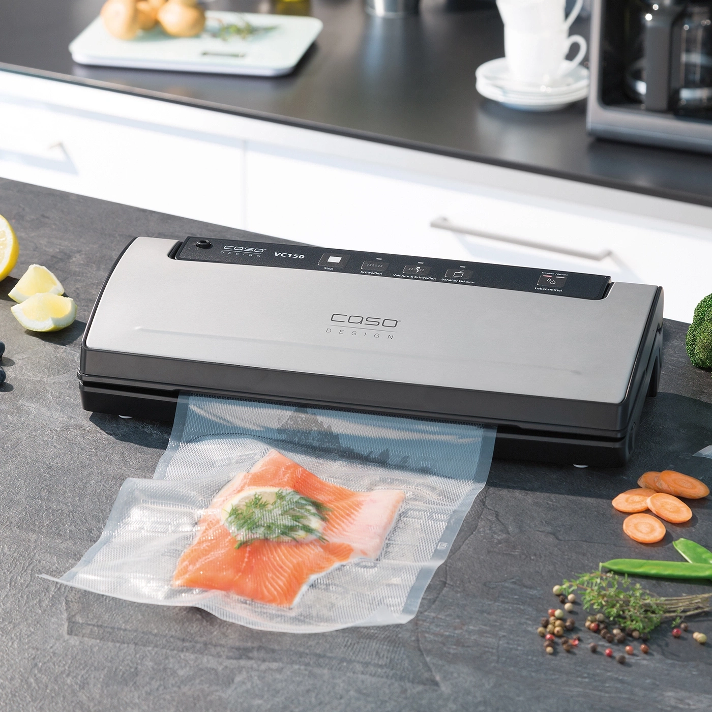 Vakuumiergerät mit Fisch und Gemüse auf einer Arbeitsplatte in der Küche.