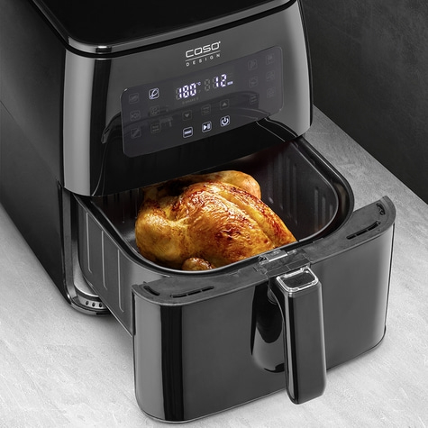 Black air fryer with roasted chicken, ready for cooking, kitchen appliance.