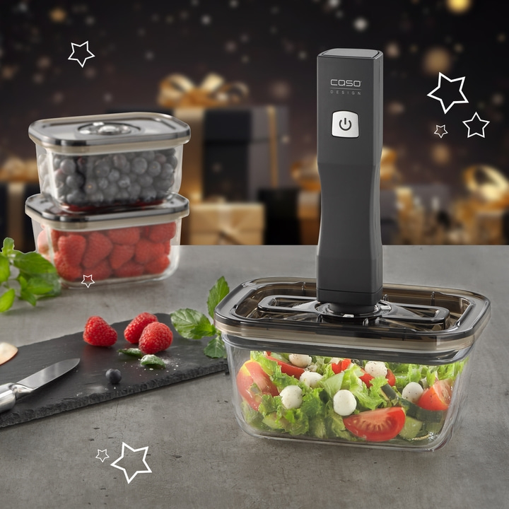 Vakuumiergerät mit Behältern und Lebensmitteln, Salat und Beeren.