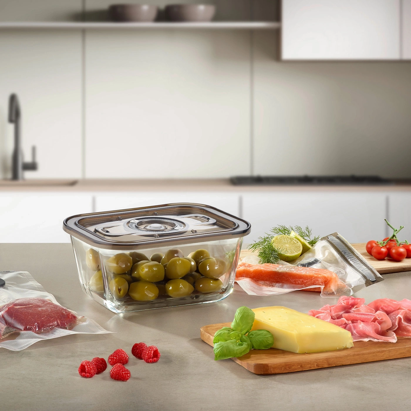 Lebensmittel auf einer Küchenarbeitsplatte: Oliven, Himbeeren, Käse, Lachs, Tomaten.