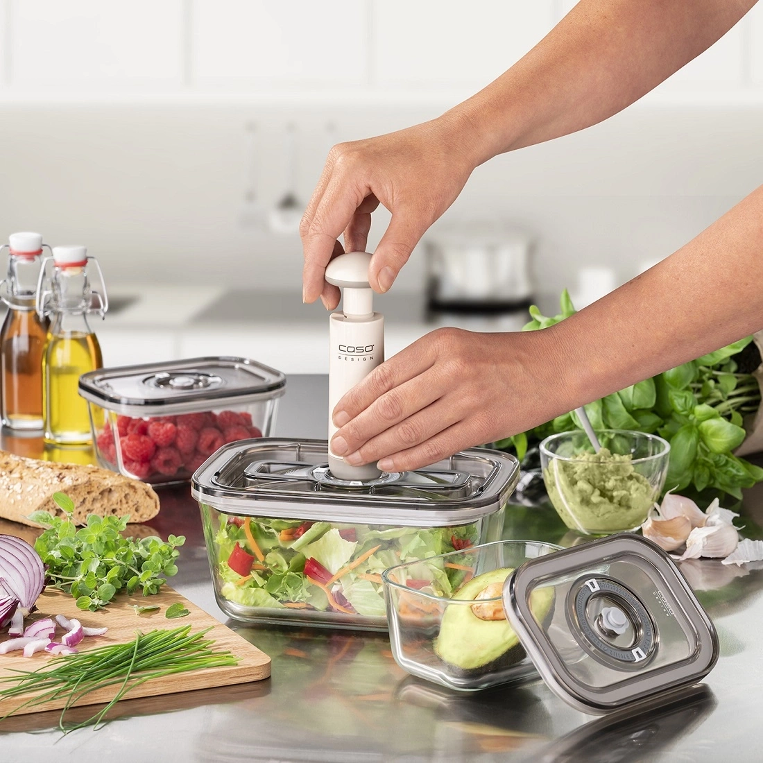 Person benutzt Vakuumpumpe auf Glasbehälter mit Salat und Avocado.