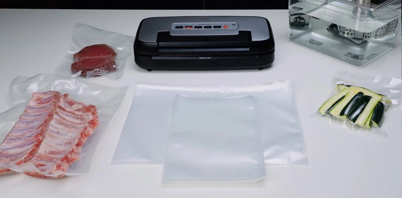 Vakuumiergerät mit Fleisch und Gemüse in Beuteln, bereit zum Sous-Vide-Garen.