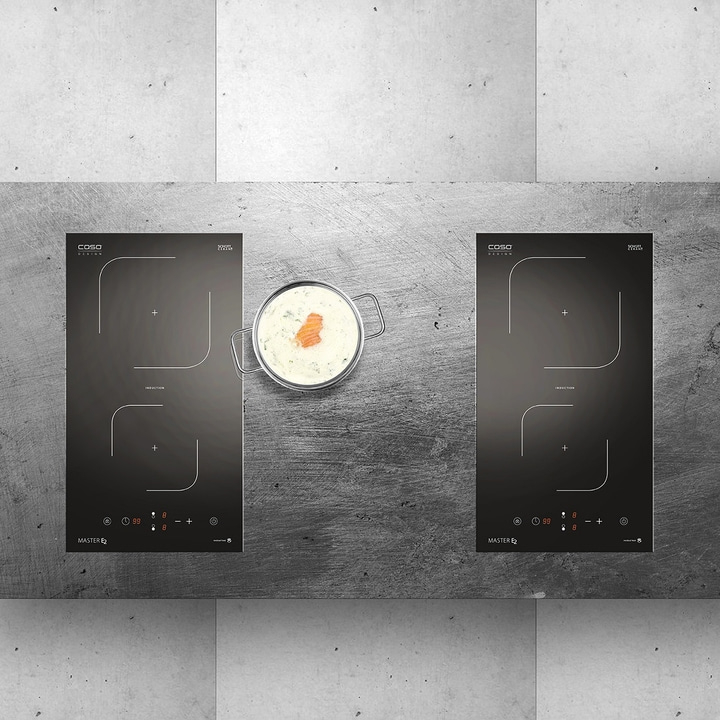 Two induction cooktops with a pot of food, gray background, Caso Design, cooking.