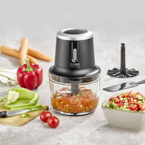 Food processor with vegetables, knife and ingredients on a table