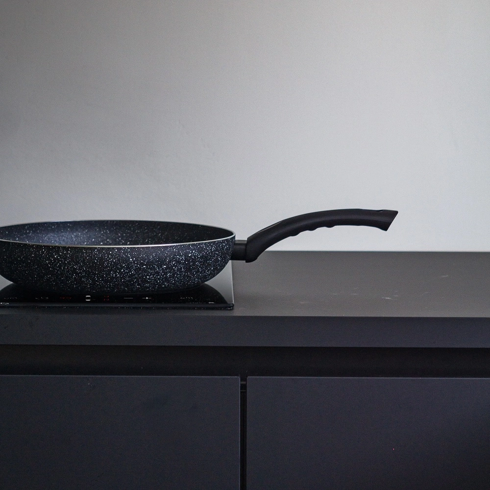 Frying pan on stove in dark kitchen, close-up shot