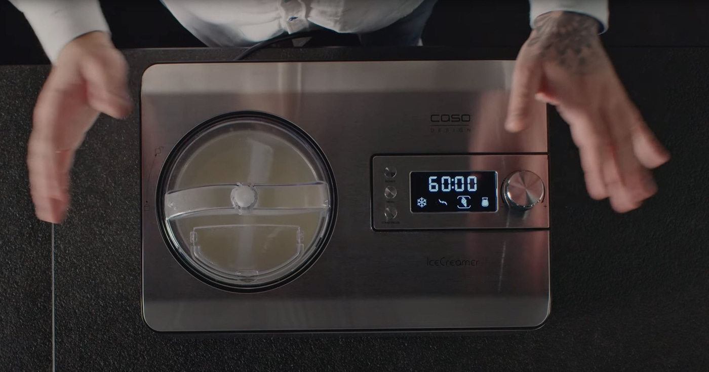 Eiscreme-Maschine mit Händen, die sie umgeben, und einer Anzeige von 60:00 Minuten.
