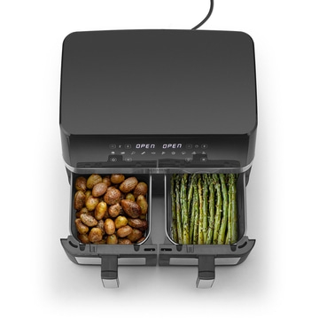 Schwarze Heißluftfritteuse mit Kartoffeln und Spargel, von oben gesehen.