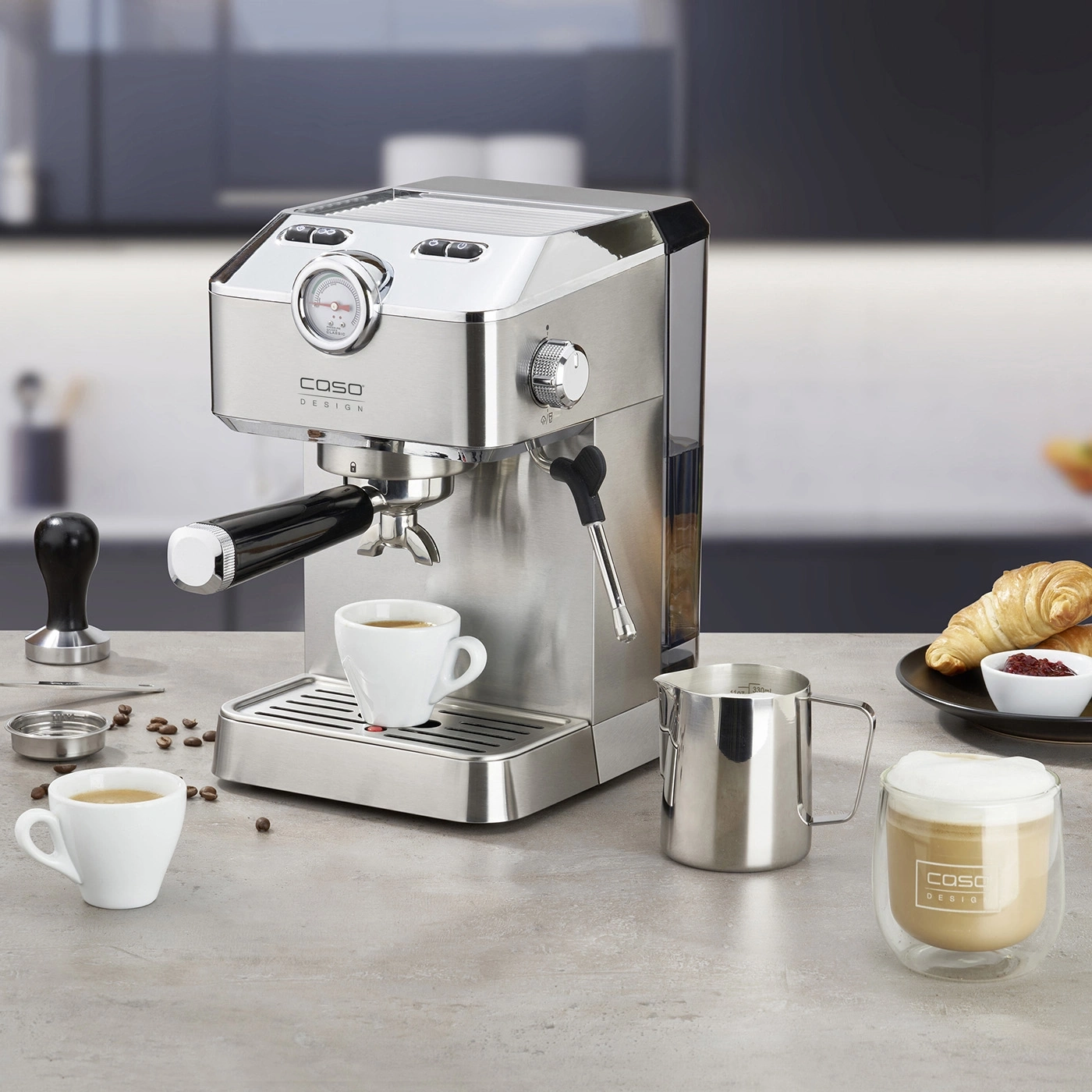Espresso machine with accessories, coffee, and pastries on a table