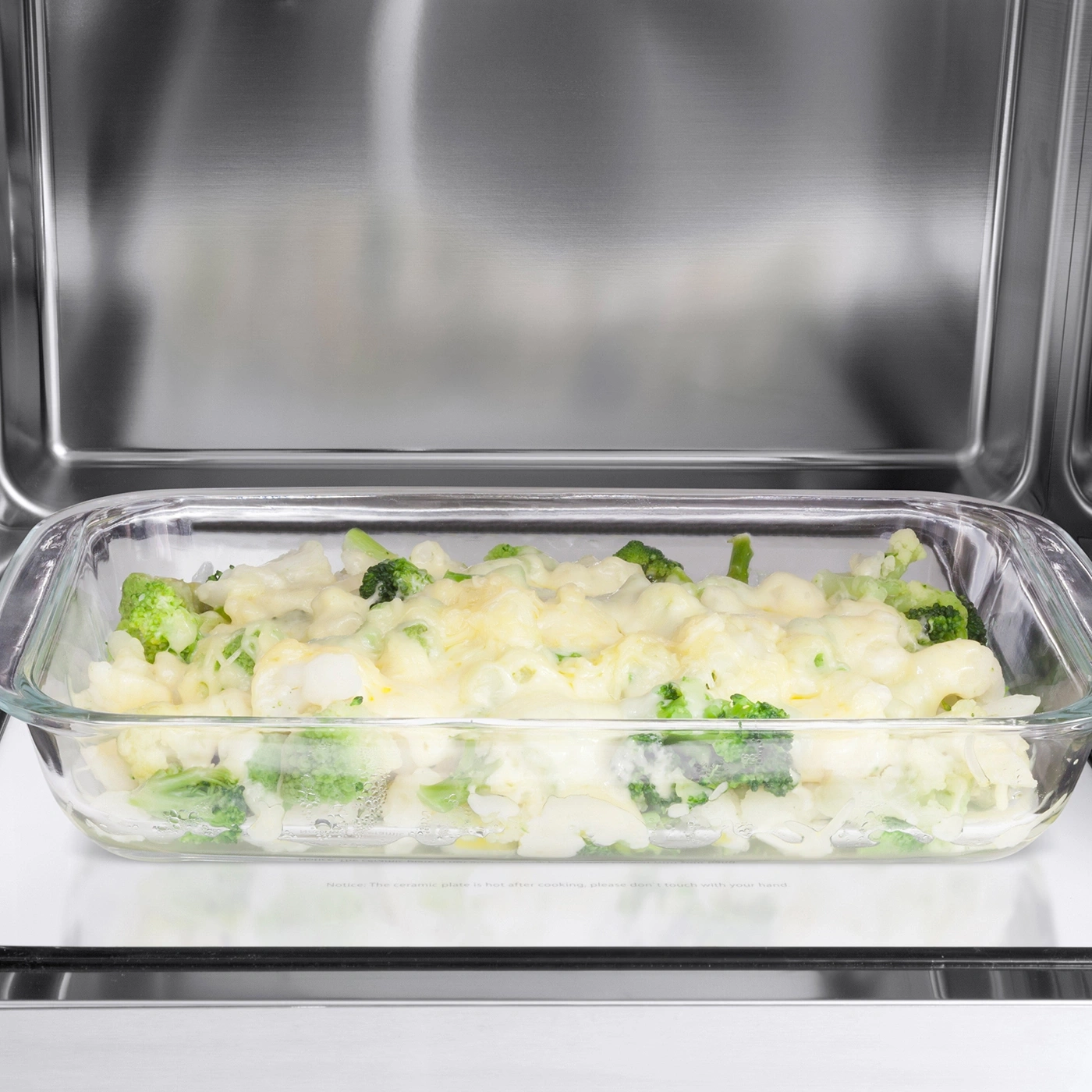 Brokkoli-Auflauf in Glasform im Ofen. Käse bedeckt Gemüse.
