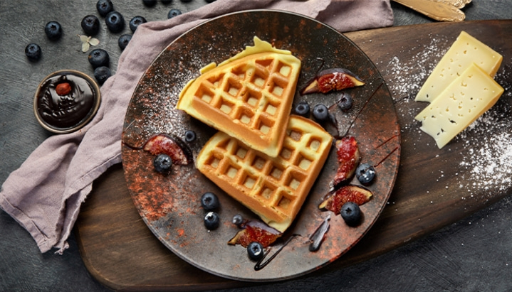 Waffles with blueberries, figs, and cheese on a rustic plate