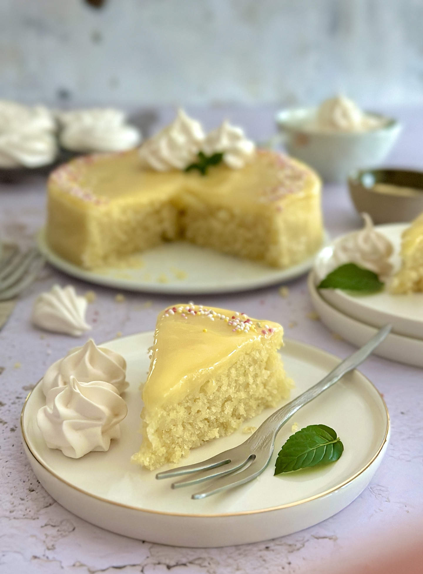 Kuchenstück mit Glasur und Dekoration auf einem Teller mit Gabel und Minze.