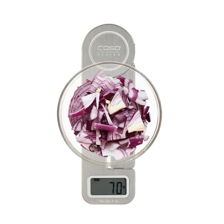 Onions on a scale. Chopped onions in a glass bowl. Weight: 70g. Kitchen scale.
