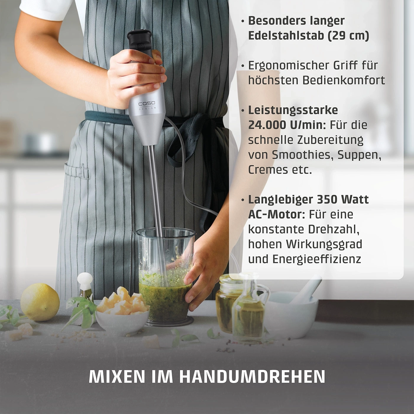 Ein Handmixer mit Edelstahlstab mixt grüne Zutaten in einem Glas.