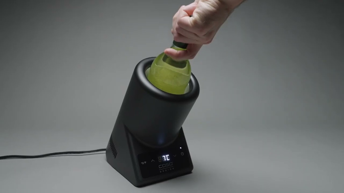 Eine Person, die eine Flasche in ein schwarzes Gerät steckt, um sie zu kühlen.