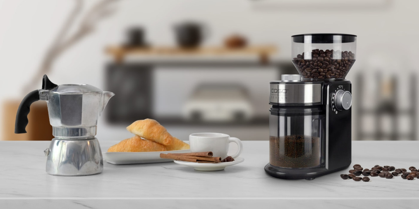 Kaffeemaschine, Kaffeebohnen, Croissants, Tasse, Zimtstangen auf dem Tisch