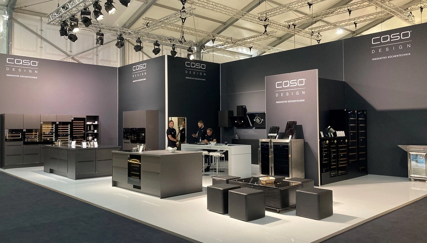 Küchenausstellung mit Caso Design, dunklen Möbeln und Beleuchtung.