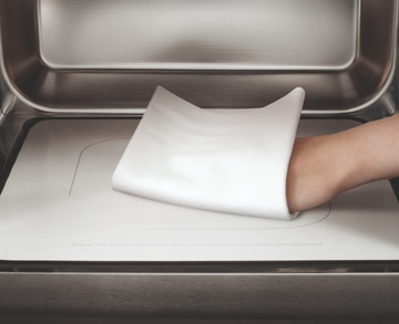 Hand berührt heiße Platte. Vorsicht, die Platte ist heiß! Nicht berühren!