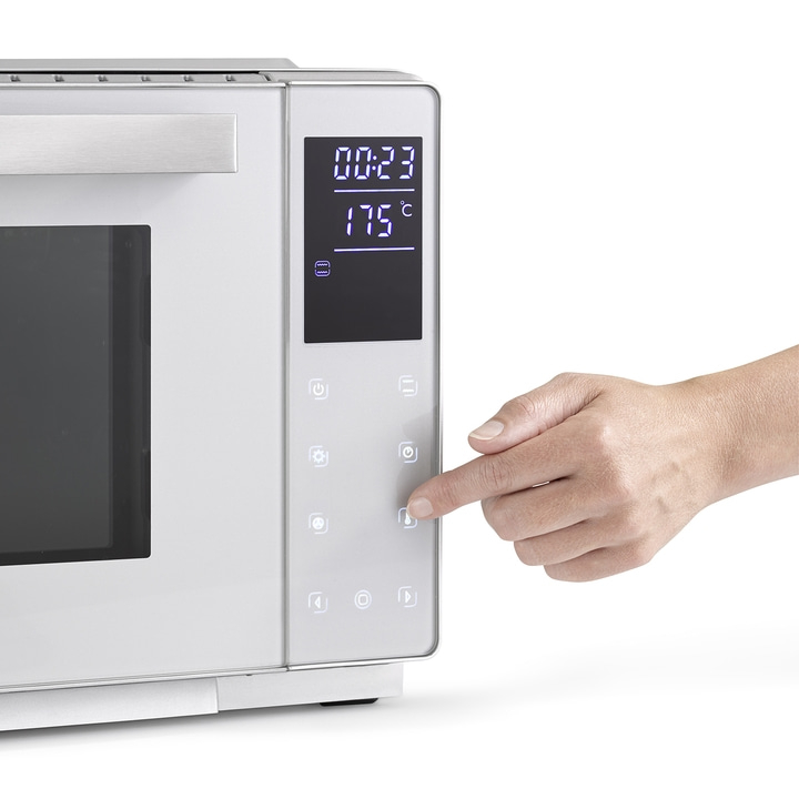 Oven with digital display and hand pressing a button to adjust the temperature.