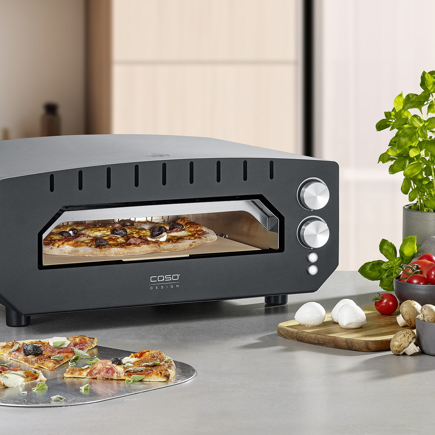 Pizza oven with pizza and ingredients on a table, ready to be served.