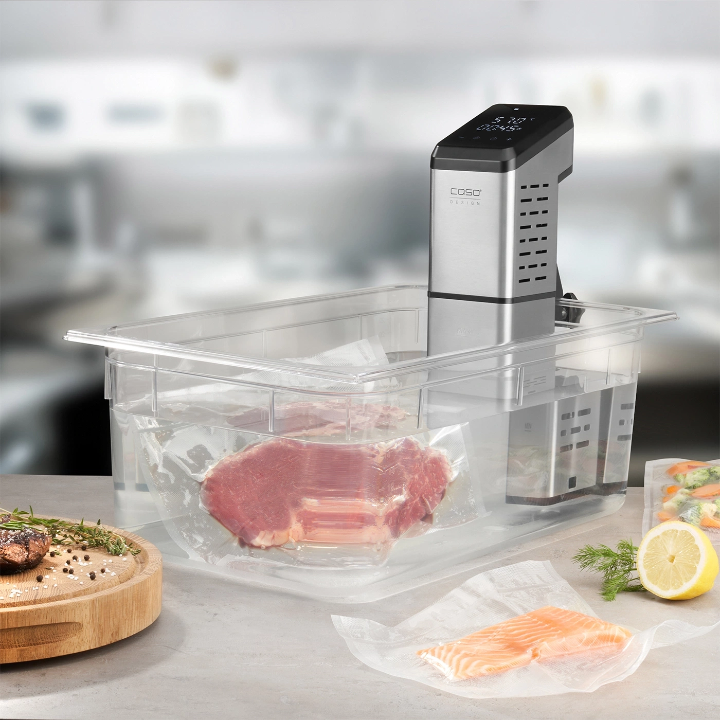 Sous vide machine with meat and fish in bags, lemon and herbs on the table.