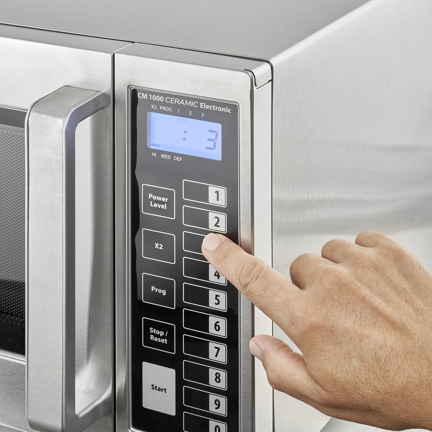 Microwave with control panel, hand pressing button 2, display shows 3, CM 1000 Ceramic Electronic
