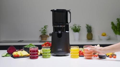 Black juicer with juice glasses and fruits on a white table