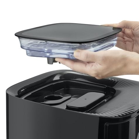 Hands holding a black container above another black container, close up.