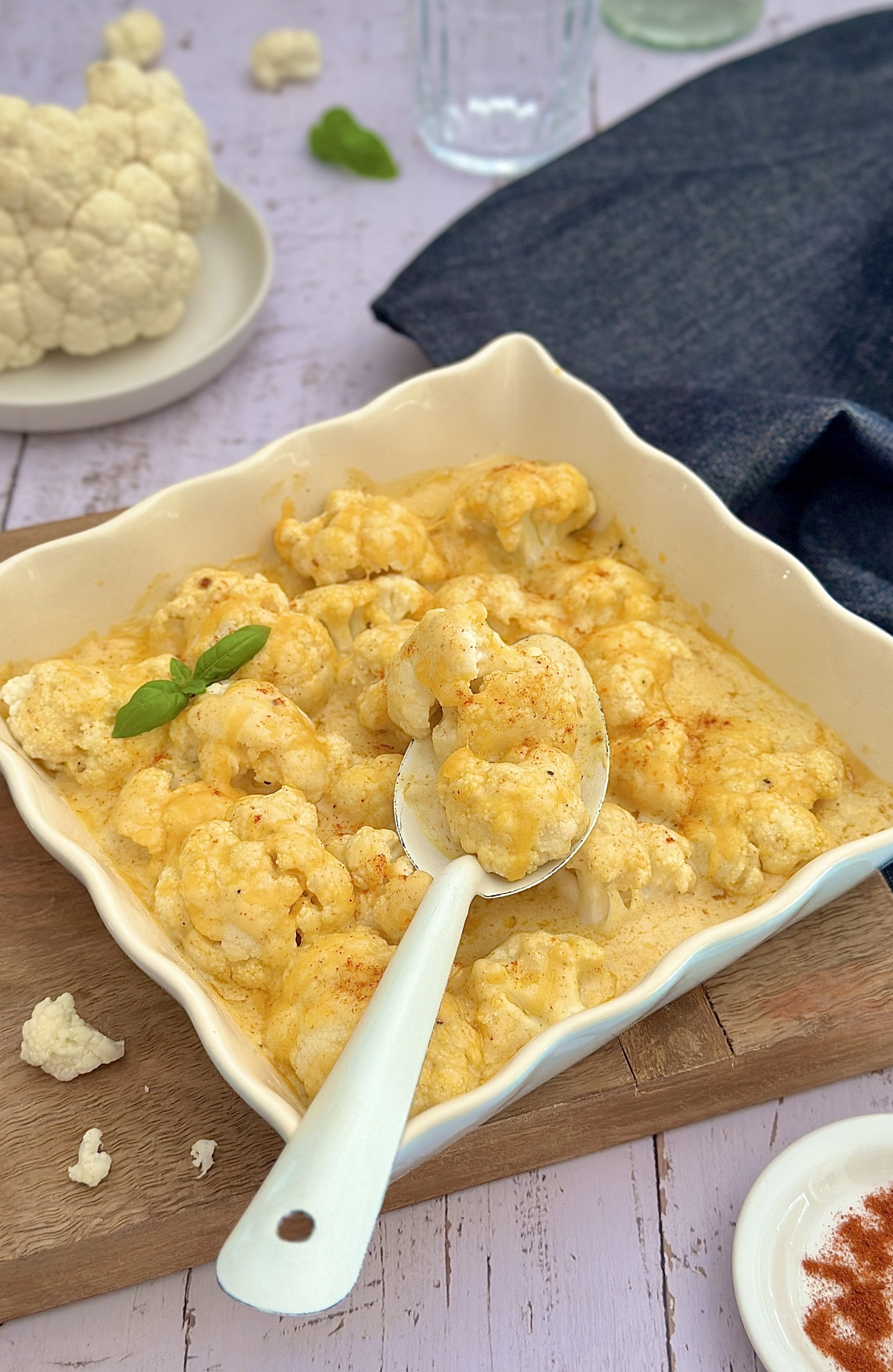 Käse-Blumenkohl-Auflauf in einer weißen Auflaufform mit Basilikum