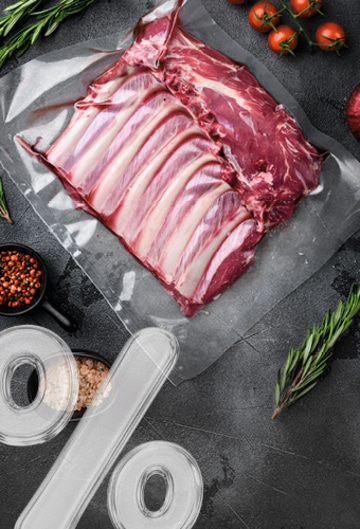 A raw lamb rack in plastic wrap with spices and herbs.