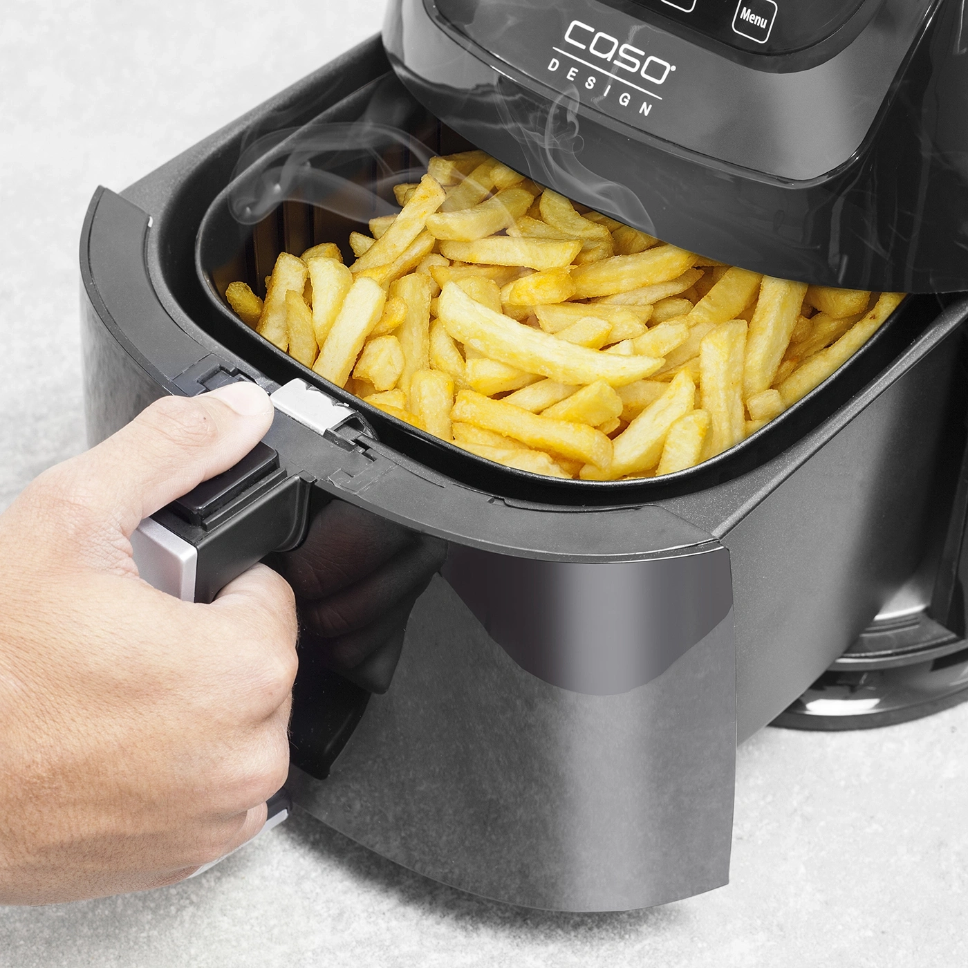French fries in an air fryer being opened, with steam rising from the food.