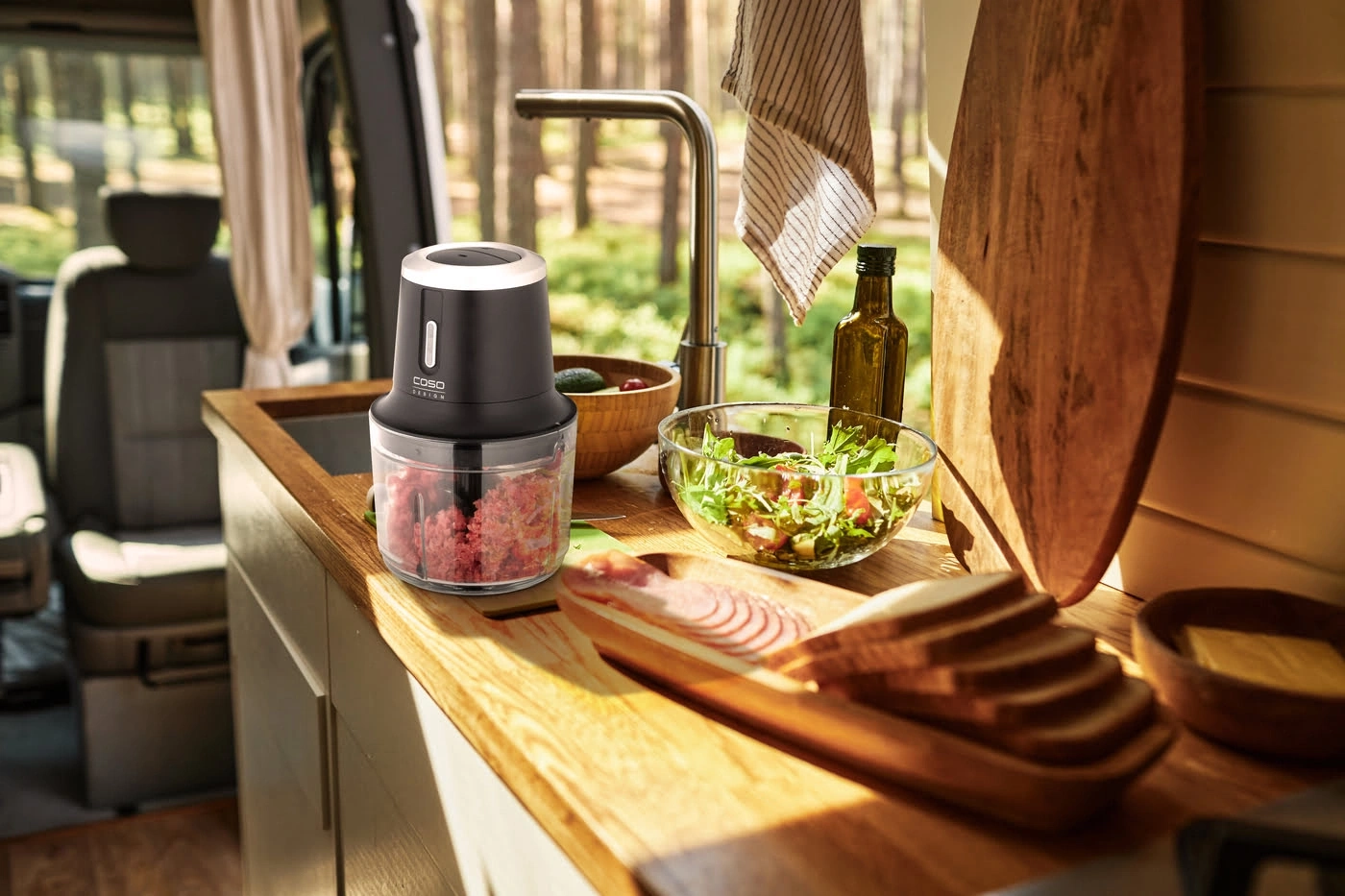 Küchenszene mit Mixer, Salat, Brot und Zutaten in einem Wohnmobil.