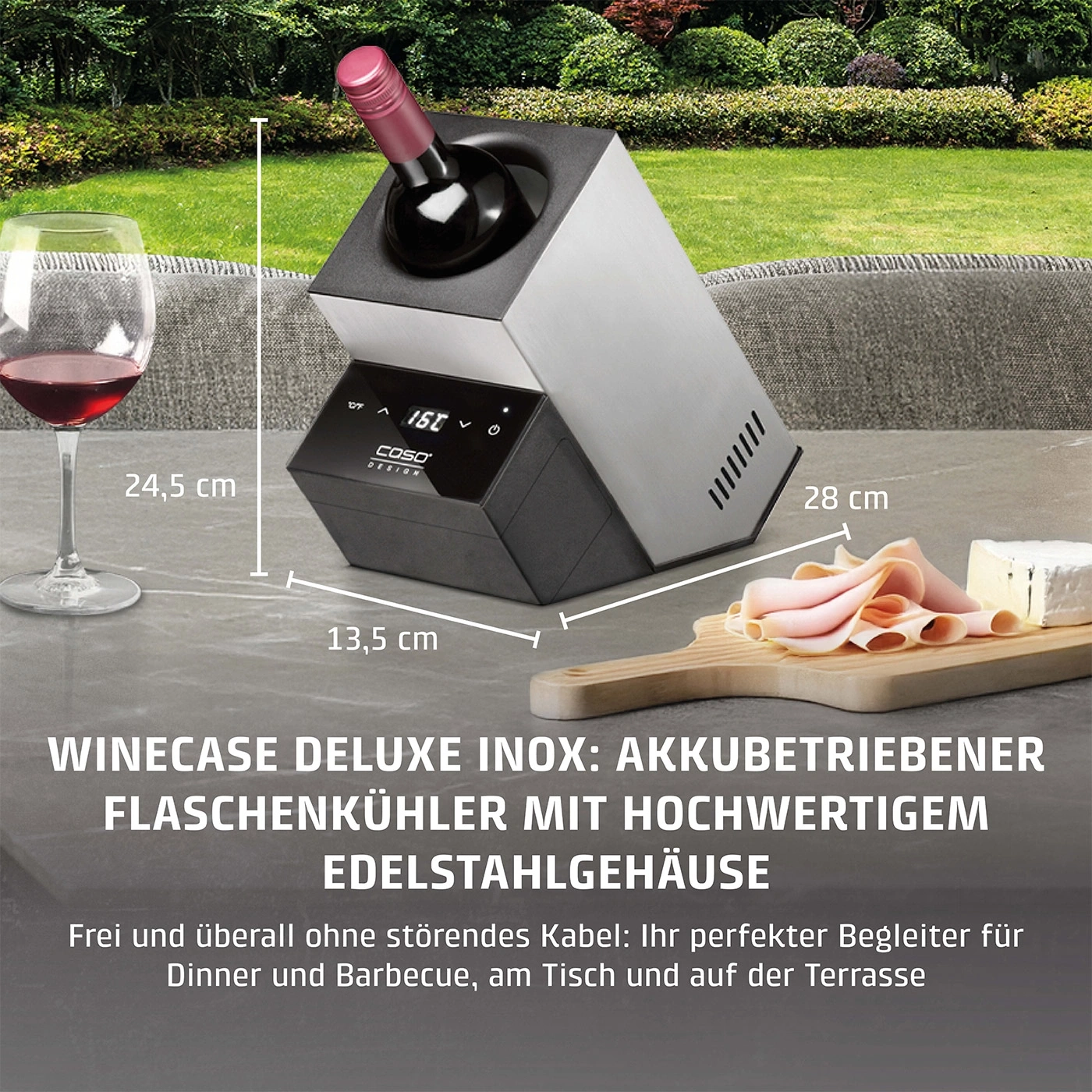 Weinkühler mit Wein, Glas, Käse und Wurst auf dem Tisch im Garten.