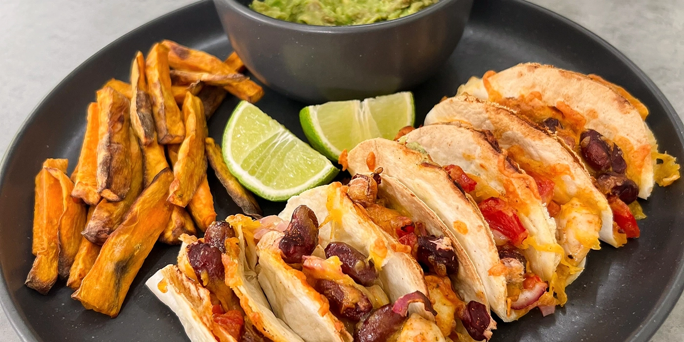 Teller mit Tacos, Pommes und Guacamole, Limettenscheiben