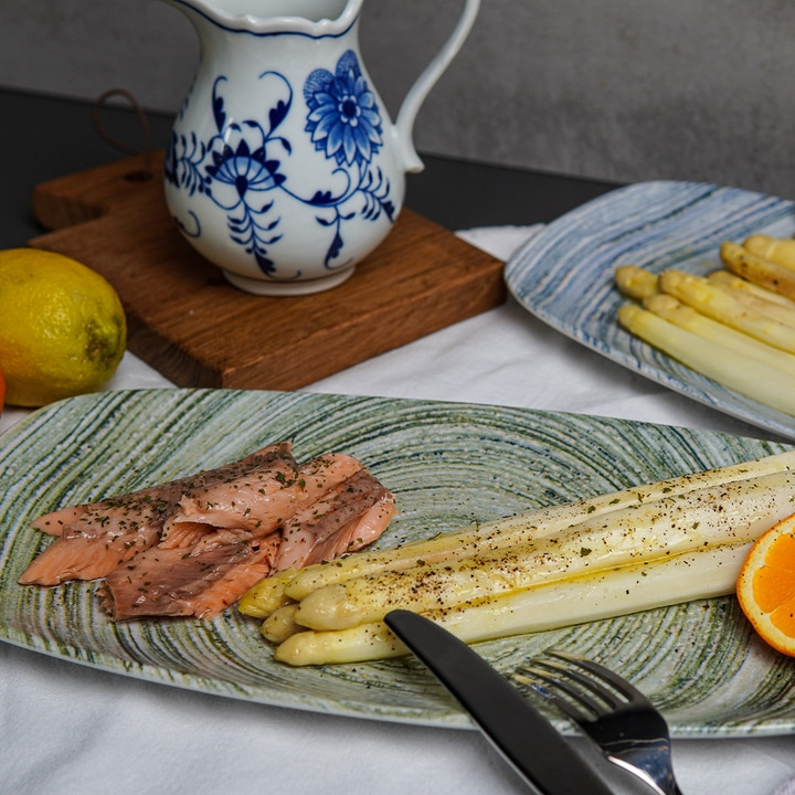Plate of asparagus, salmon, lemon, and a pitcher in the background