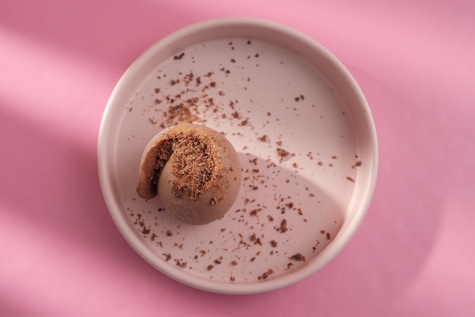 Schokoladenkuchen auf einem Teller mit rosa Hintergrund und Schatten