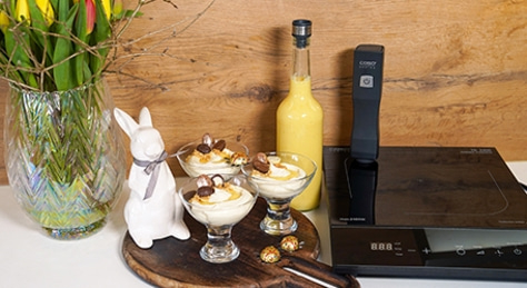 Easter dessert with chocolate eggs, bunny, flowers, and cooking utensils on wooden surface