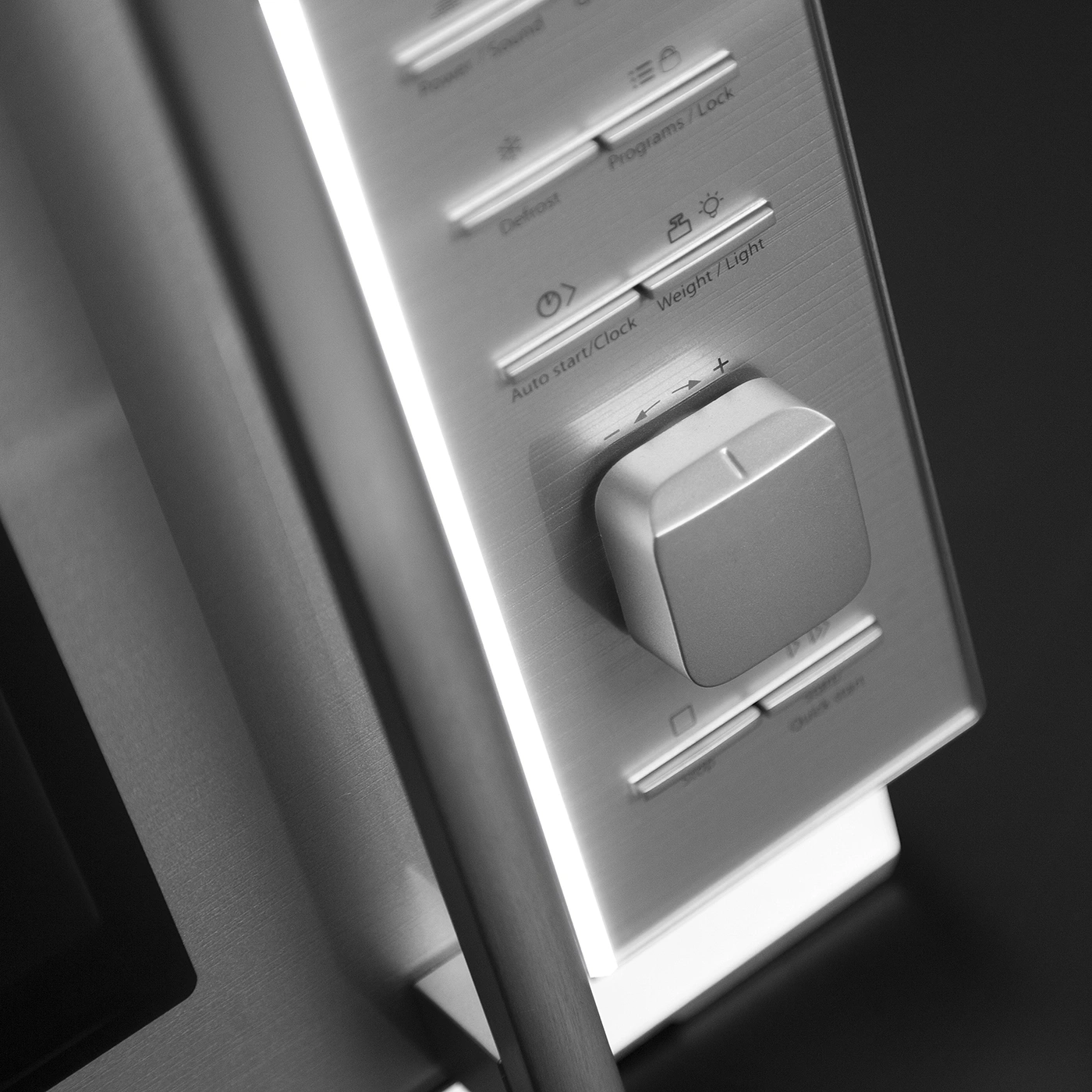 Close-up of a microwave control panel with buttons and a dial. Grayscale image.