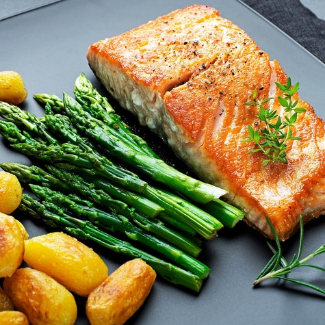 Grilled salmon fillet with asparagus and potatoes on a black plate