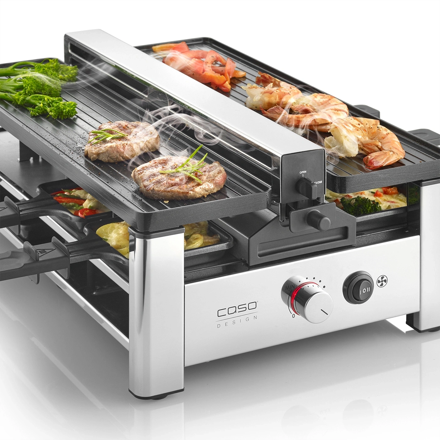 Ein Raclette-Grill mit Fleisch, Garnelen und Gemüse wird zubereitet.